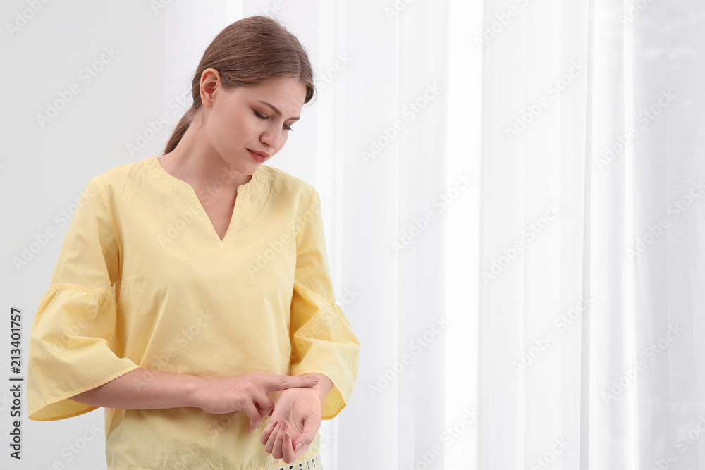 Young woman checking pulse on light background Young woman checking pulse on light background