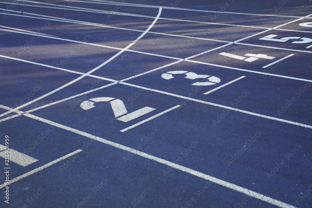Start positions of a blue outdoor stadium running track with white dividing lines