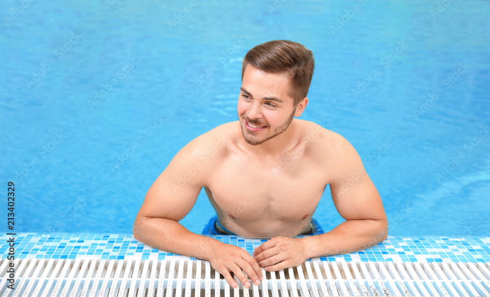 Handsome young man in swimming pool with refreshing water