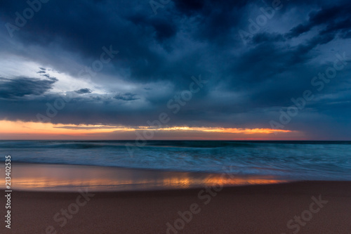 Amazing sunset on the ocean. View of dramatic cloudy sky and reflection of the sunlight on water. Atlantic coast near Lisbon. Portugal.