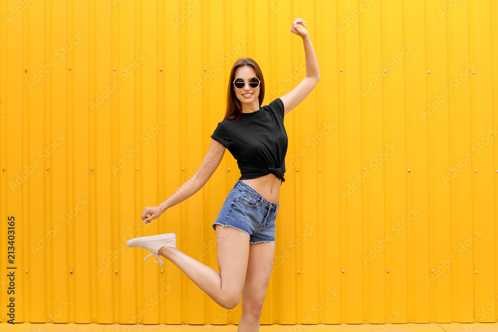 Young woman wearing black t-shirt near color wall on street