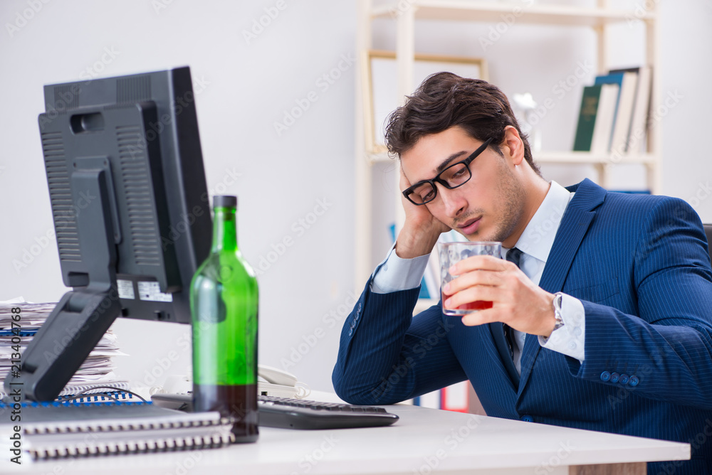 Young businessman employee drinking in the office at desk Young businessman employee drinking in the office at desk