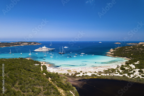 Aerial view of an emerald and transparent mediterranean sea with a white beach and some yachts. Gulf of the Great Pevero, Costa Smeralda, Sardinia, Italy.