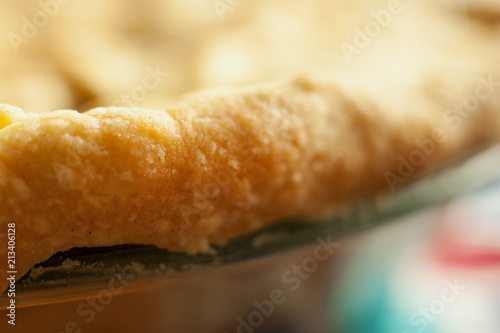 Close detail image of baked pie crust at the edge of an apple pie.  Horizontal with shallow depth of field.