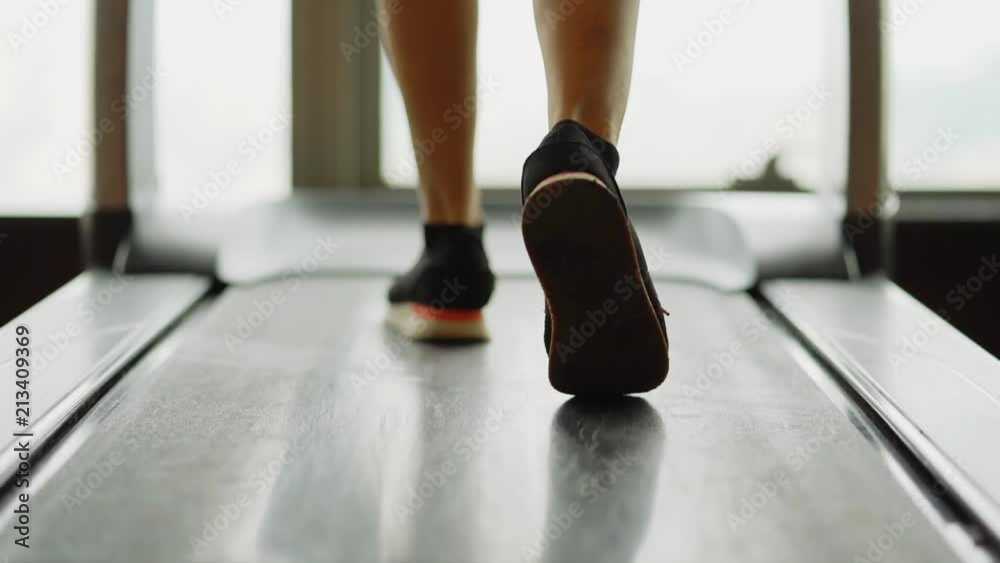 Slow motion of woman legs walking on a treadmill at gym. Exercising concept Slow motion of woman legs walking on a treadmill at gym. Exercising concept