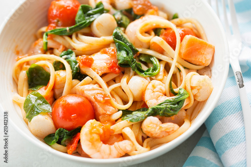Seafood linguine with prawns, scallops and salmon, spinach and tomatoes photo