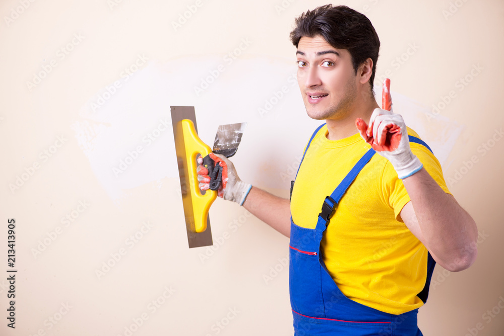 Young contractor employee applying plaster on wall Young contractor employee applying plaster on wall