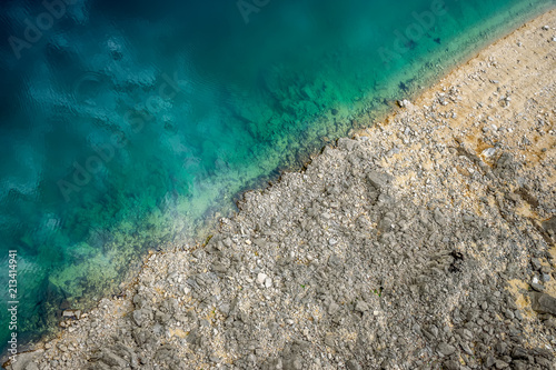 A picturesque place where transparent turquoise water meets a stony shore.
