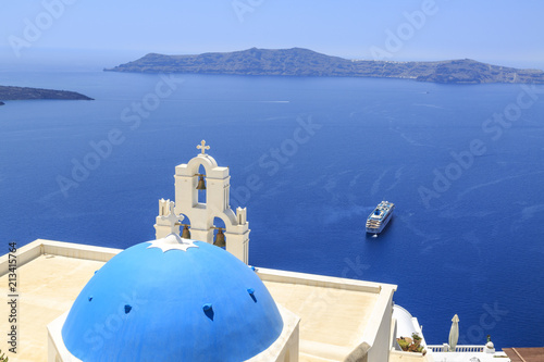 Three bells of Fira Church in Fira, Santorini island, Greece with cruise ship on sea