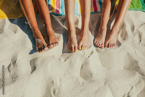 Close up of legs of three women at the beach