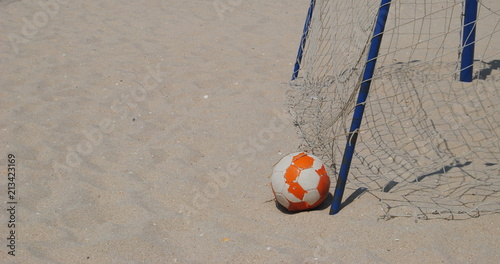 Futebol o desporto dos pobres - bola de futebol velha deixada na praia junto de uma baliza com as redes rompidas - futebol de praia photo