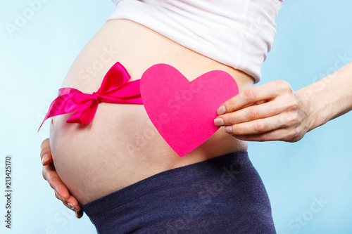 Wallpaper Mural Pregnant woman holding heart and touching her belly with pink ribbon, concept of expecting for newborn girl Torontodigital.ca