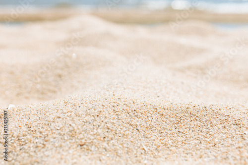 Sand close-up, against the background of a blurred blue sea or ocean, an empty beach, Sunny day
