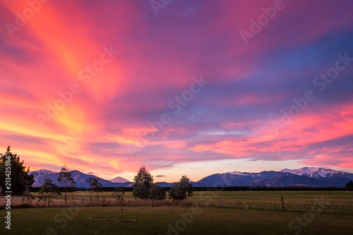 A purple and orange fiery sunset over a rural landscape