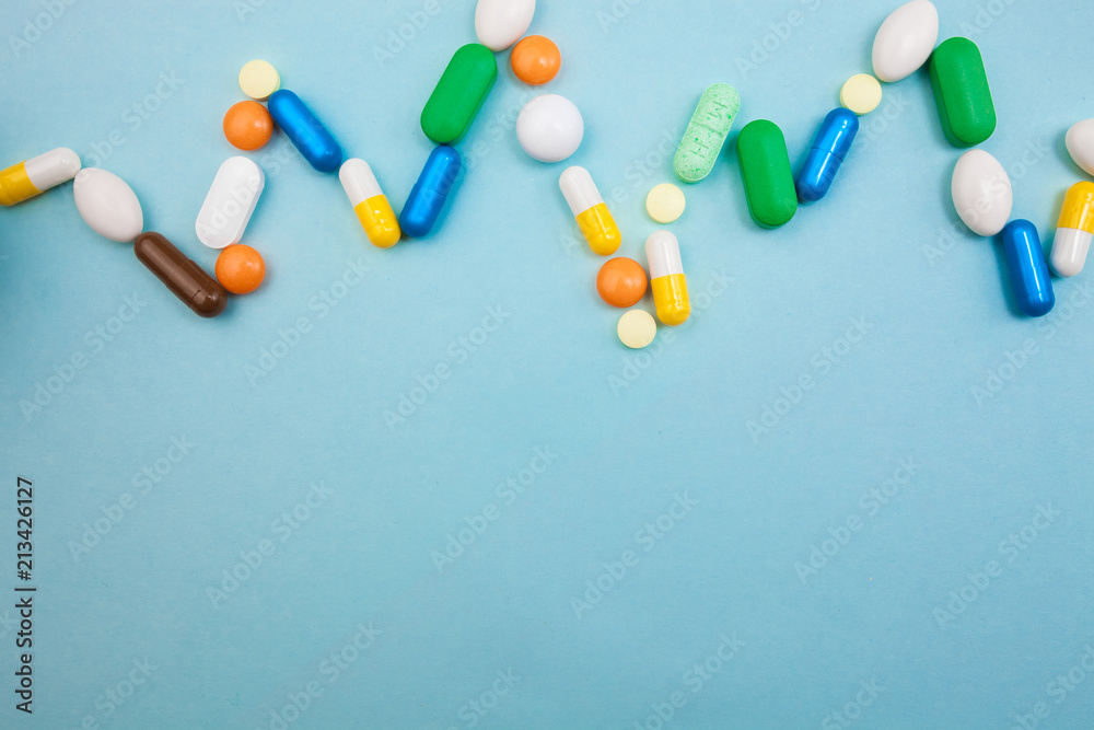 Multi-colored tablets and capsules in pulsation heartbeat white bottle for tablets, pharmaceutical medicine pills on blue background, an analgesic against diseases Multi-colored tablets and capsules in pulsation heartbeat white bottle for tablets, pharmaceutical medicine pills on blue background, an analgesic against diseases