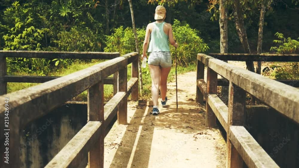 Girl is walking along an abandoned bridge in the jungle Girl is walking along an abandoned bridge in the jungle