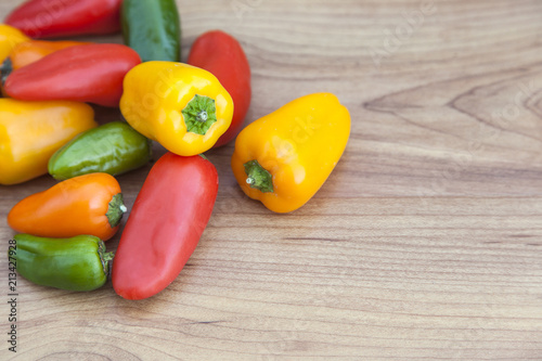 Fresh red, green, yellow and orange peppers (capsicum) on wooden background wih copy space