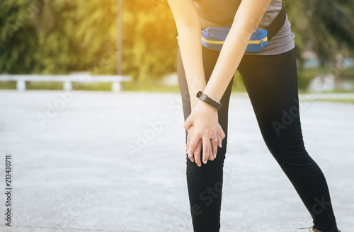 Woman suffering from pain in leg injury after sport exercise running jogging and workout outdoo,Hand touching her knee