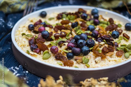 Oatmeal granola porridge with banana, dried fruits, honey and berries. Dates, dried grape, honey, blueberry, raspberry and oats for morning breakfast. Vegan vegetarian healthy food and paleo diet