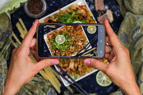 Smartphone food photography. Phone photo of Asian fried noodles with vegetables, prawn and octopus meat cooked in soy sauce. Traditional authentic food in asian cafe or restaurant. Eat with chopsticks photo