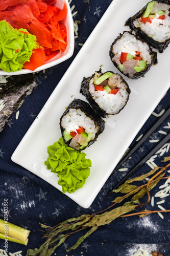 Homemade vegetarian sushi rolls with chopsticks with tofu, rice, cucumber, avocado, carrot, sour gari - pickled red ginger and wasabi wrapped into nori seaweed. Raw vegan vegetarian healthy food