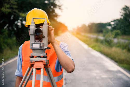 Survey by theodolite concept. Civil Engineer Checking Surveyor Equipment Tacheometer or theodolite outdoors at construction site on the road. photo