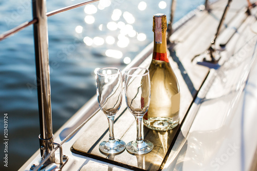 Romantic luxury evening on cruise yacht with champagne setting. Empty glasses and bottle with champagne and tropical sunset with sea background, nobody. © mat_mary
