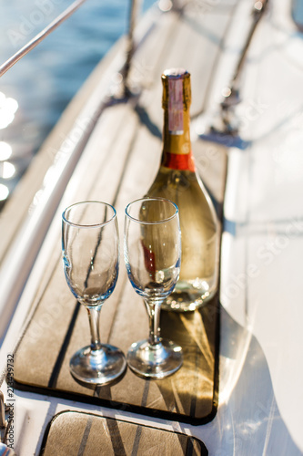 Romantic luxury evening on cruise yacht with champagne setting. Empty glasses and bottle with champagne and tropical sunset with sea background, nobody.