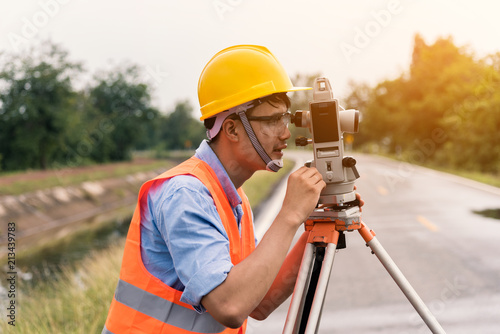 Survey by theodolite concept. Civil Engineer Checking Surveyor Equipment Tacheometer or theodolite outdoors at construction site on the road.