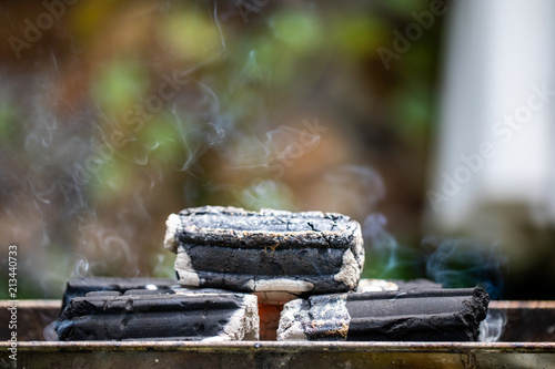 briquettes burning on charcoal grill with smoke