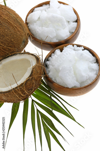 Coconut oil. organic  solid coconut oil in pieces in round wooden bowls and half fresh coconut and a palm leaf isolated on a white background.	