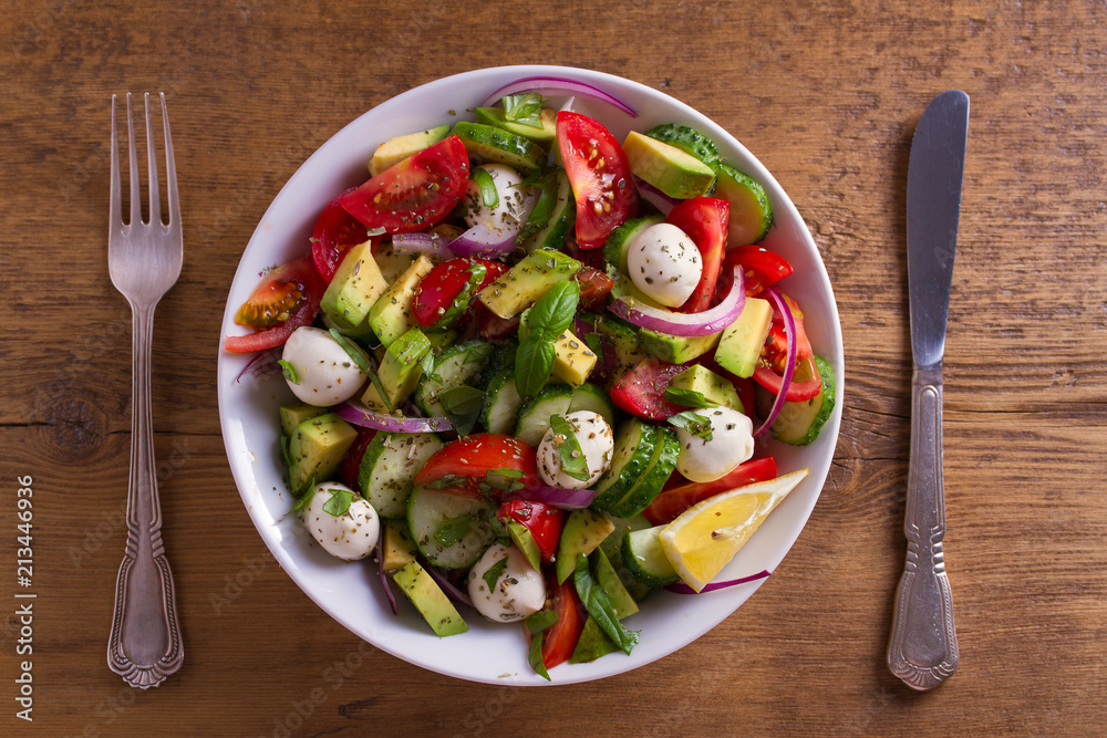 Avocado, tomato, cucumber salad with mozzarella cheese. View from above, top studio shot Avocado, tomato, cucumber salad with mozzarella cheese. View from above, top studio shot
