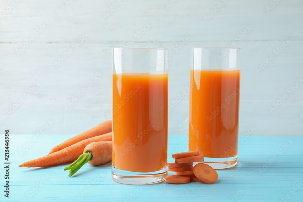 Glasses with carrot juice and fresh vegetable on wooden table Glasses with carrot juice and fresh vegetable on wooden table
