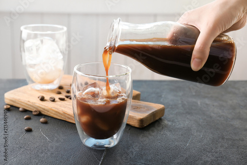 Fotobehang Woman pouring cold brew coffee into glass on table