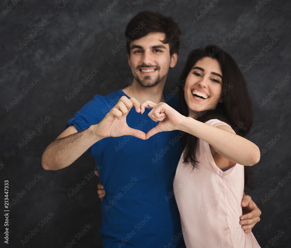 Smiling couple making heart shape by fingers Smiling couple making heart shape by fingers