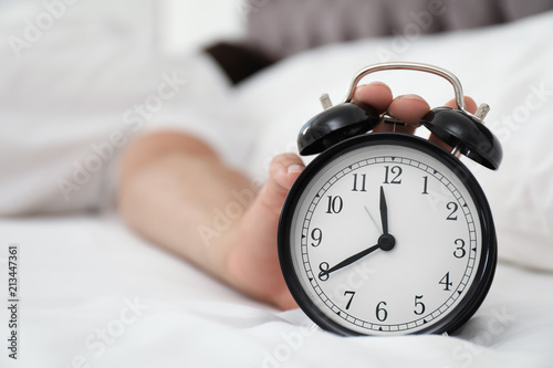 Man turning off alarm clock in bedroom