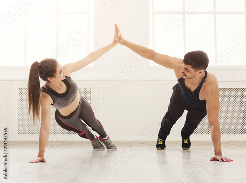 Fototapeta Naklejka Na Ścianę i Meble -  Sporty couple giving high five while doing push up