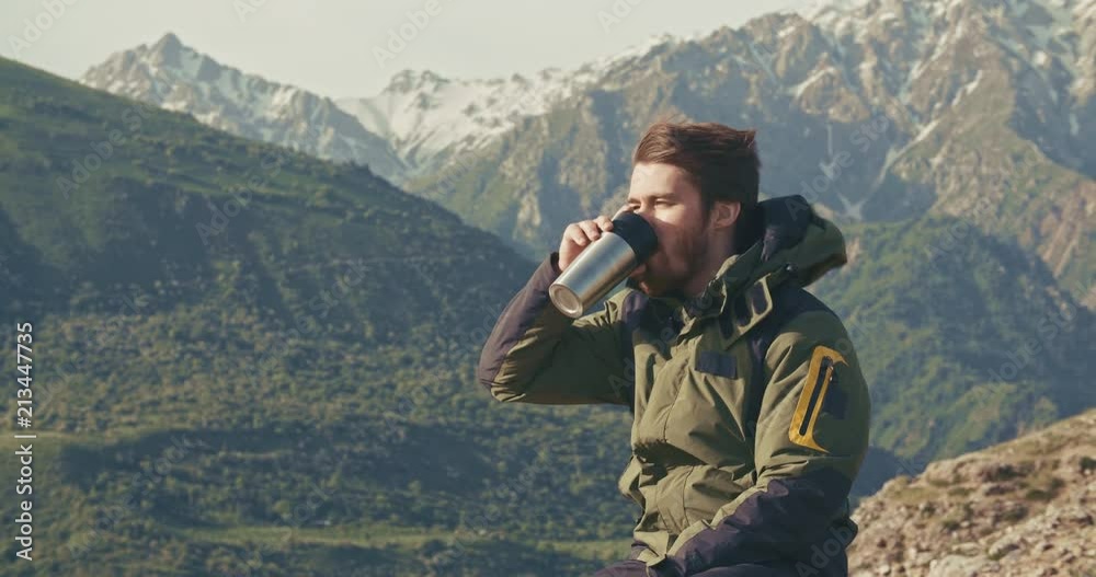 lonesome climber sitting on top of mountain, drinking coffee in thermos. adventurer relaxing after achieving a goal. zen, freedom concept 4k lonesome climber sitting on top of mountain, drinking coffee in thermos. adventurer relaxing after achieving a goal. zen, freedom concept 4k