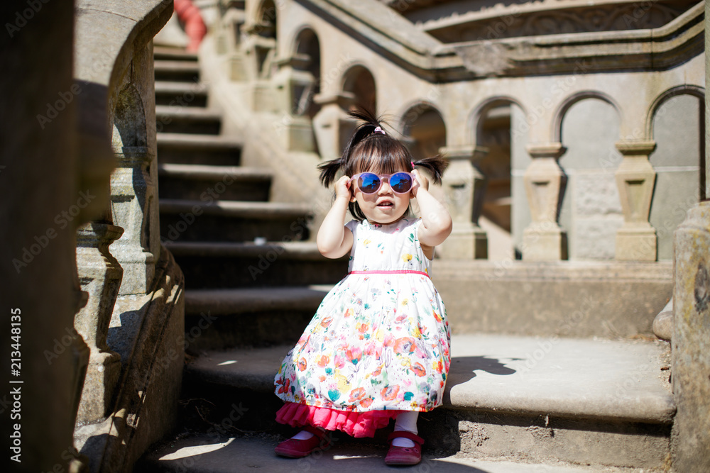 Baby girl wearing sunglasses sitting on an old staircase
