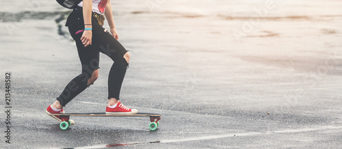 girl with ripped jeans and red sneakers riding longbord on the street