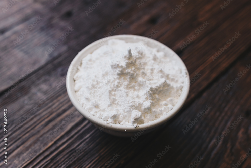 Sugar powder in a bowl on the wooden surface Sugar powder in a bowl on the wooden surface