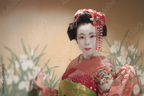 Japanese Maiko or geisha in red kimono coifed hair brooch with patterns of red and white plum blossoms