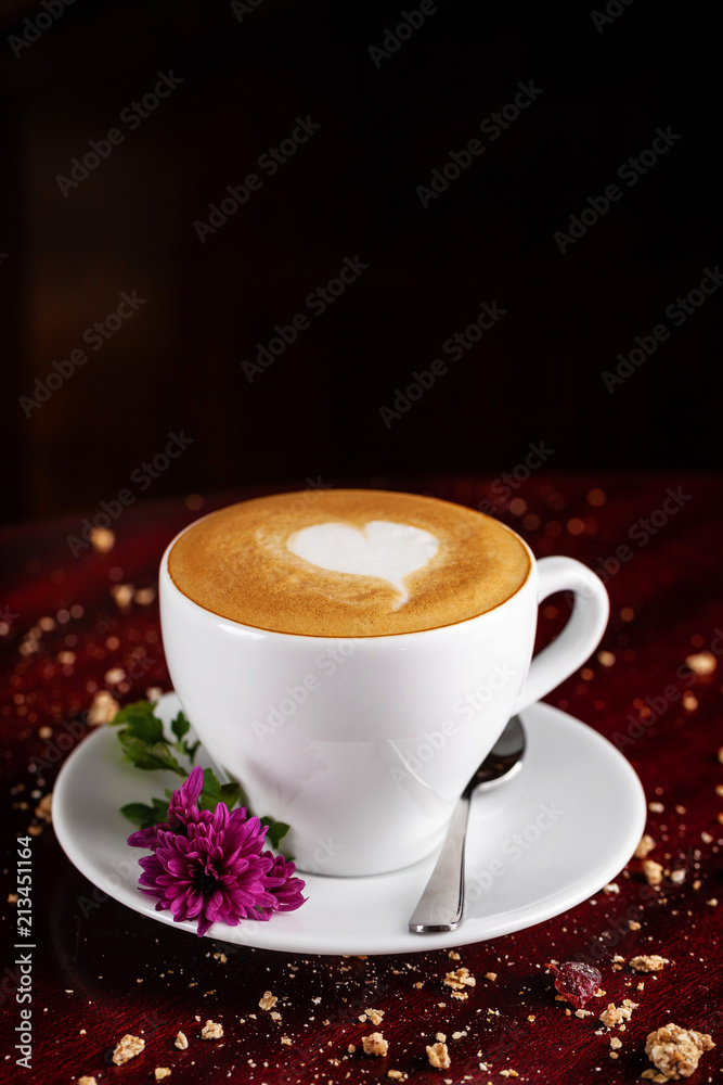 coffee cappuccino in a white cup with an art drawing in the form of a heart on the dervevyano table, clock alarm clock stand on the table. concept with a good morning. Copy space, selective focus coffee cappuccino in a white cup with an art drawing in the form of a heart on the dervevyano table, clock alarm clock stand on the table. concept with a good morning. Copy space, selective focus