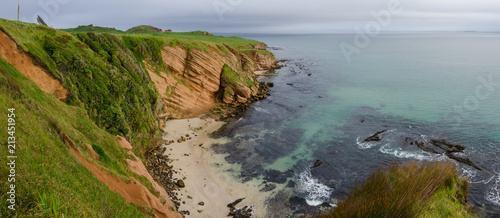 Elevated view of red sandstone cliffs and a small beach on the Chatham Islands, New Zealand. 