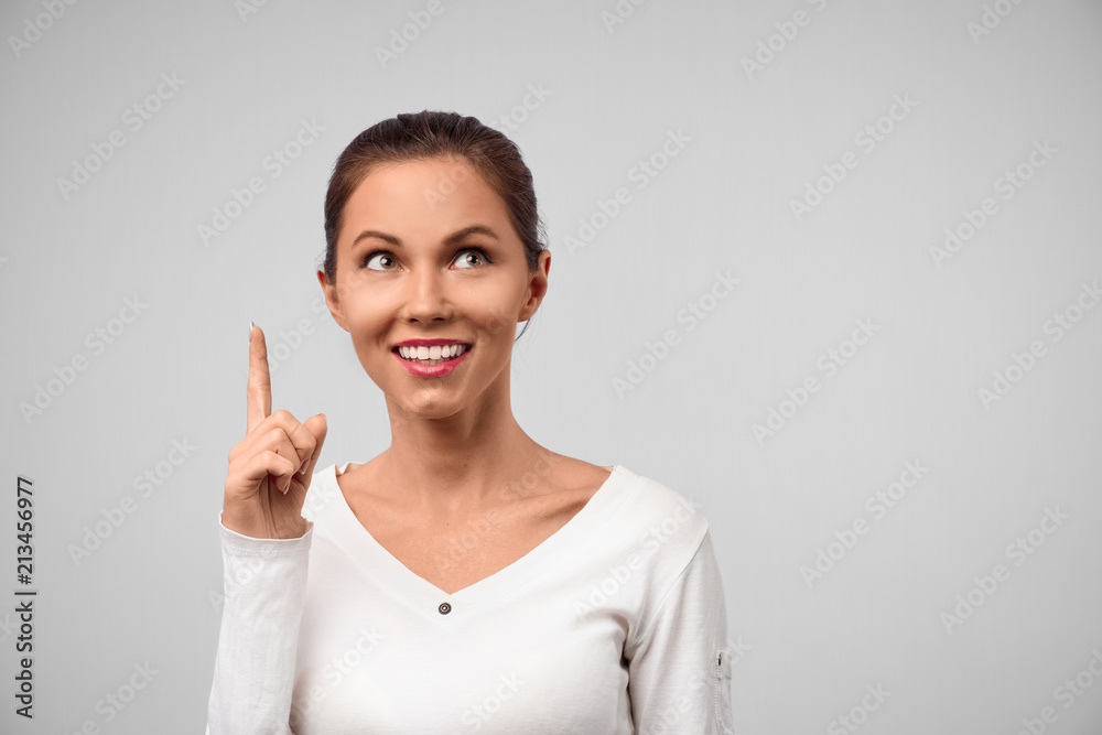 She found answer. Studio shot of beautiful creative european woman raising index finger up and smiling broadly, being in great mood after making up great plan or suggestion, happy to share it She found answer. Studio shot of beautiful creative european woman raising index finger up and smiling broadly, being in great mood after making up great plan or suggestion, happy to share it