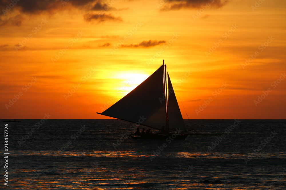 Silhouette of sailboat at sunset in Boracay White Beach, Philippines. Leisure activity at twilight. Summer vacation, relax, travel destination concepts