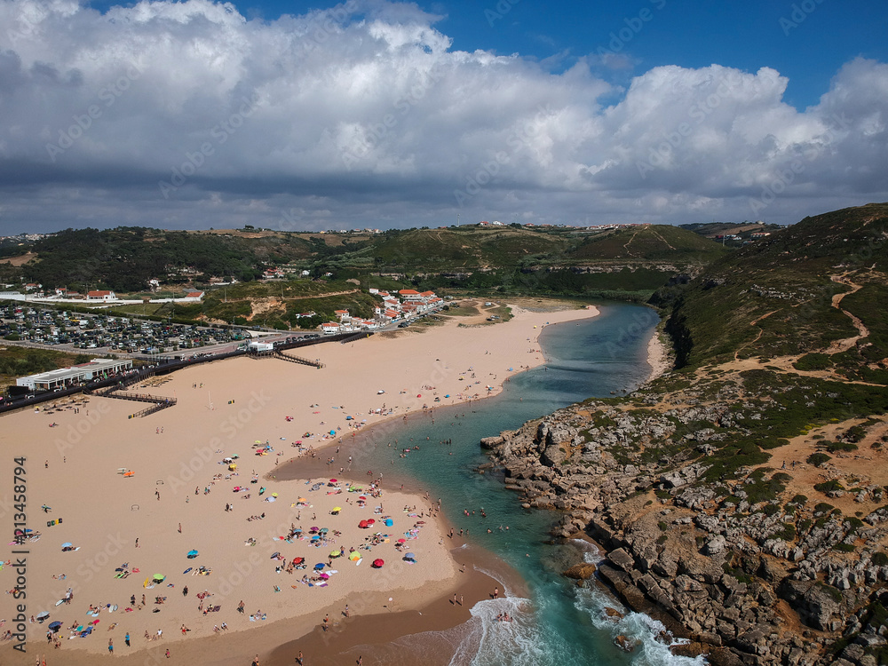 Aerial view from a beach with a river flows out to the Ocean. Foz do lizandro beach in ericeira, Portugal.