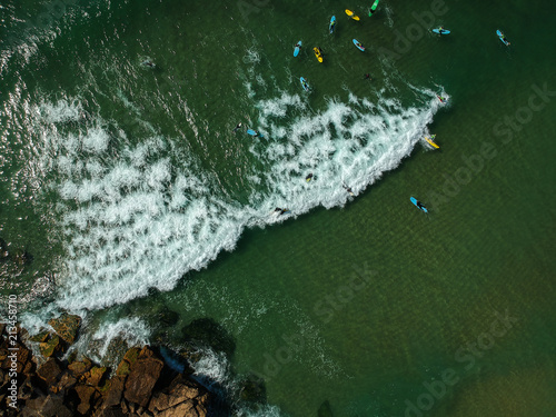 Aerial view of surfers in the ocean on a summer day. Surf Spot on the Portuguese coastline. Drone shot.