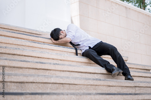 Asian businessman professional failed or upset in his job and sitting on staircase. Business problem concept. © srijaroen