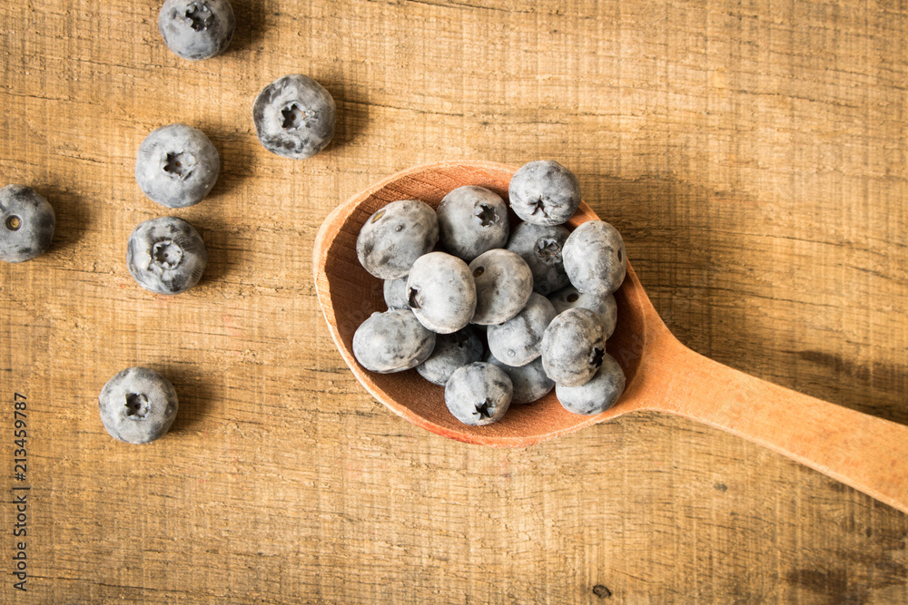 Fresh blueberries in a wooden spoon. On an old wooden table. The concept of natural food . Top view Fresh blueberries in a wooden spoon. On an old wooden table. The concept of natural food . Top view